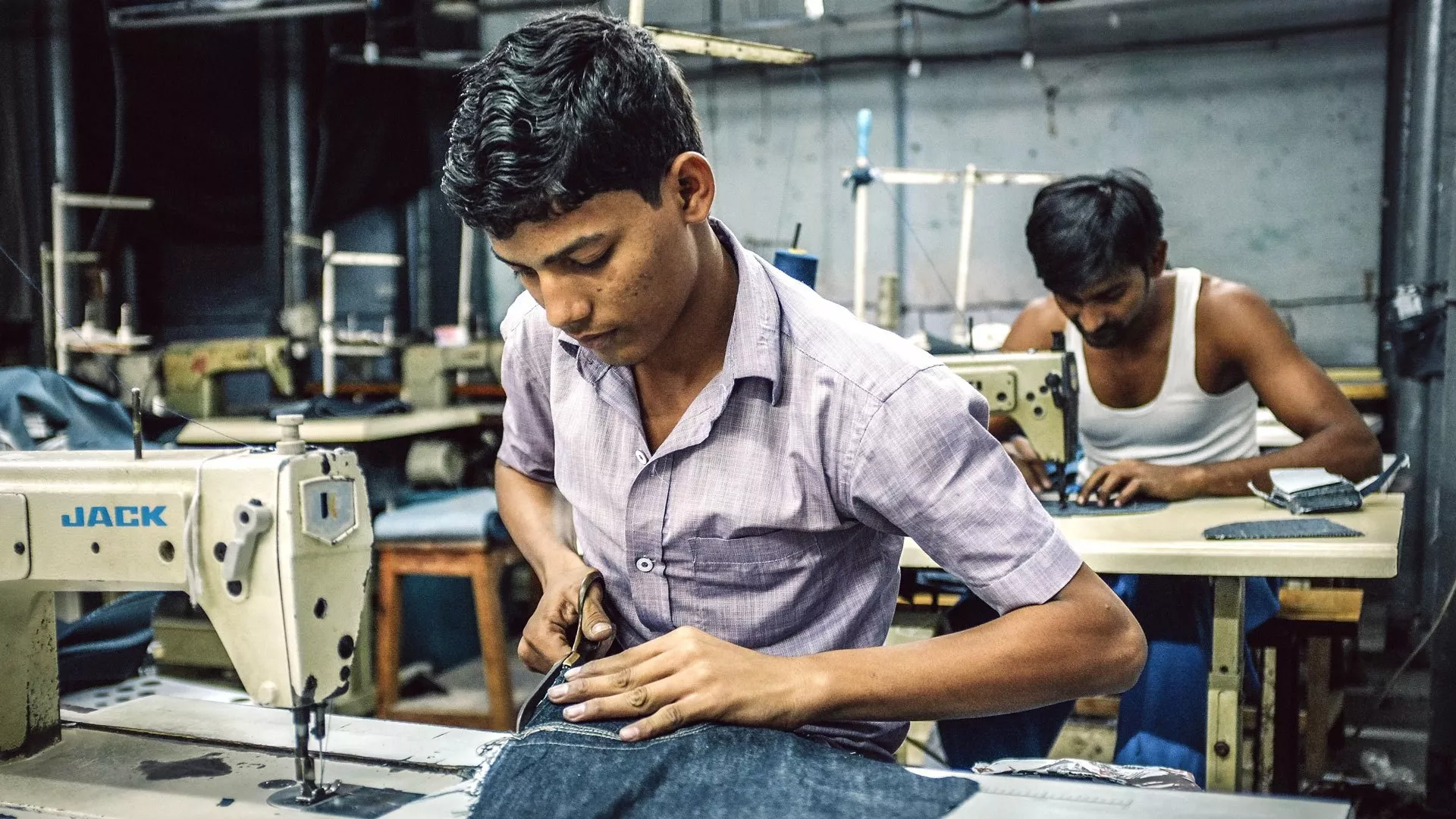 Indische Arbeiter nähen in einer Bekleidungsfabrik im Slum von Dharavi